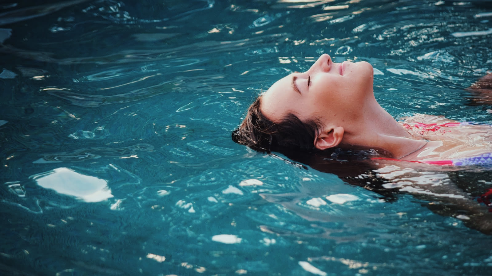 Photo d'une femme qui se détend dans l'eau d'une piscine les yeux fermés