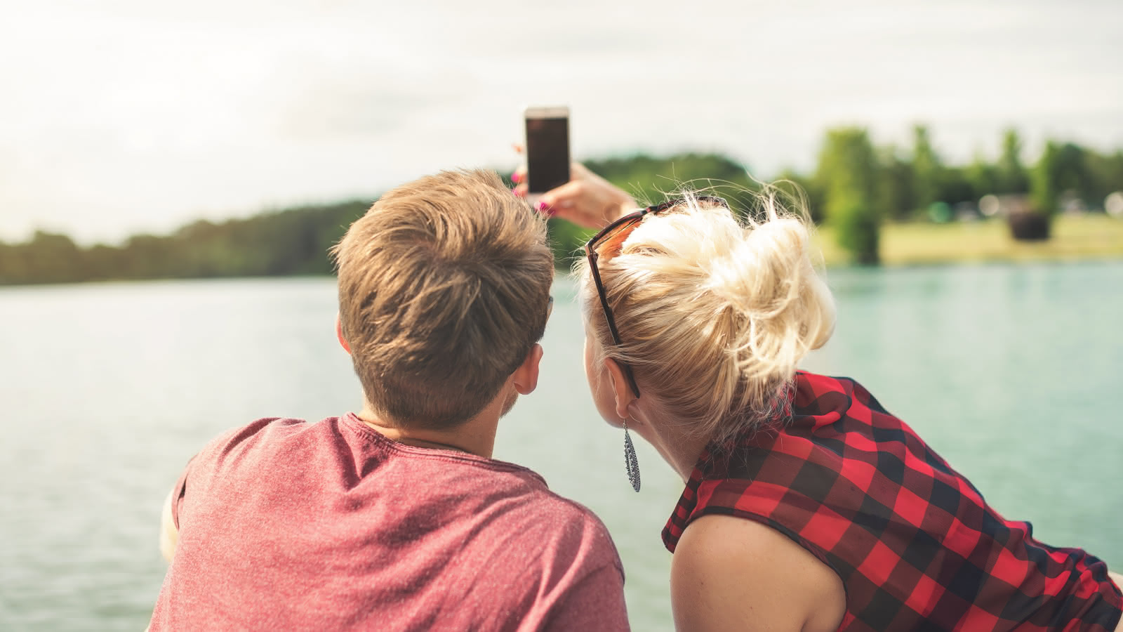 Photo d'un couple se prenant en photo selfie avec un téléphone portable sur le ponton d'un lac