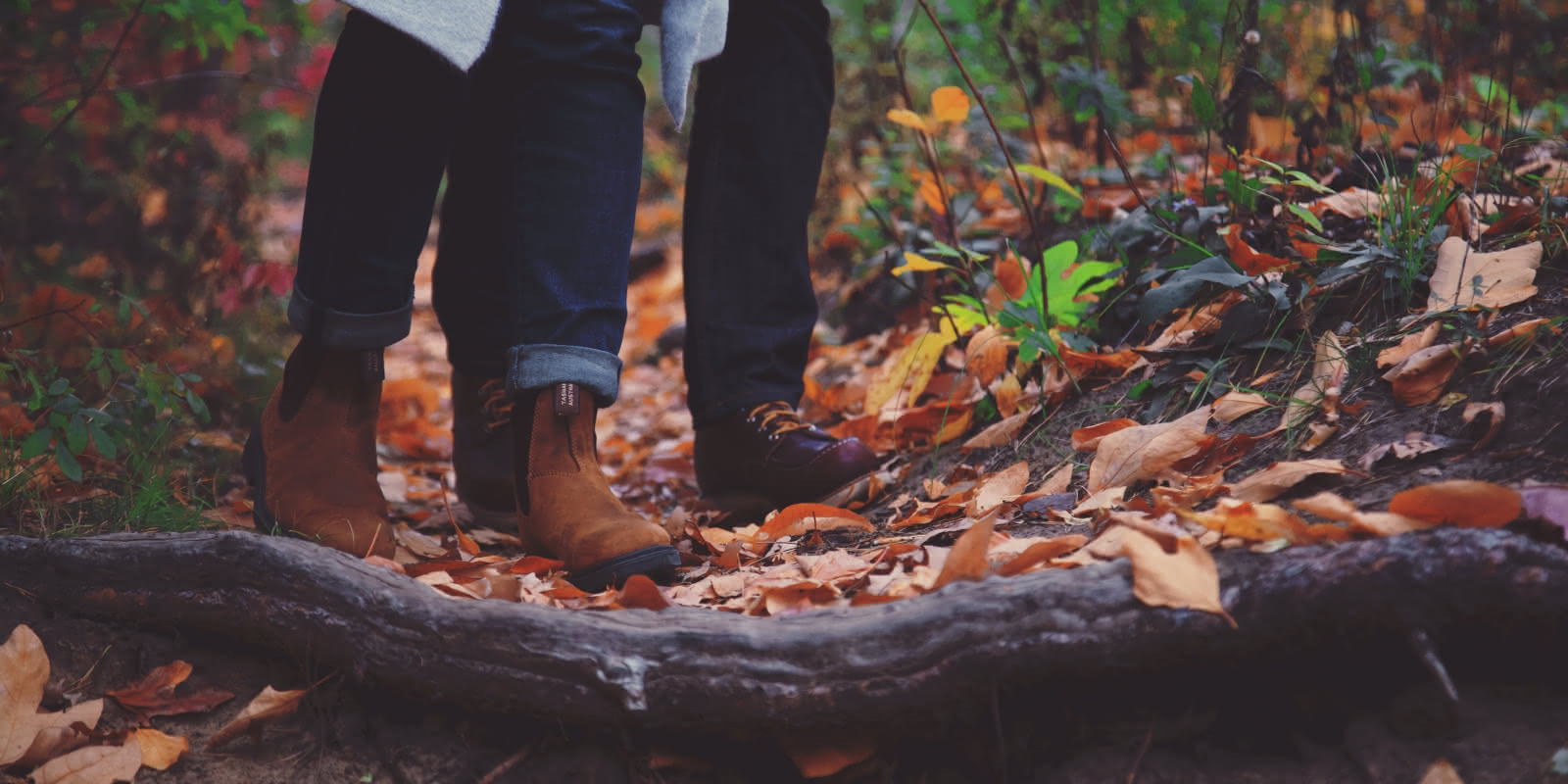 Photo d'un couple qui marche en forêt et dont on ne voit que les pieds.