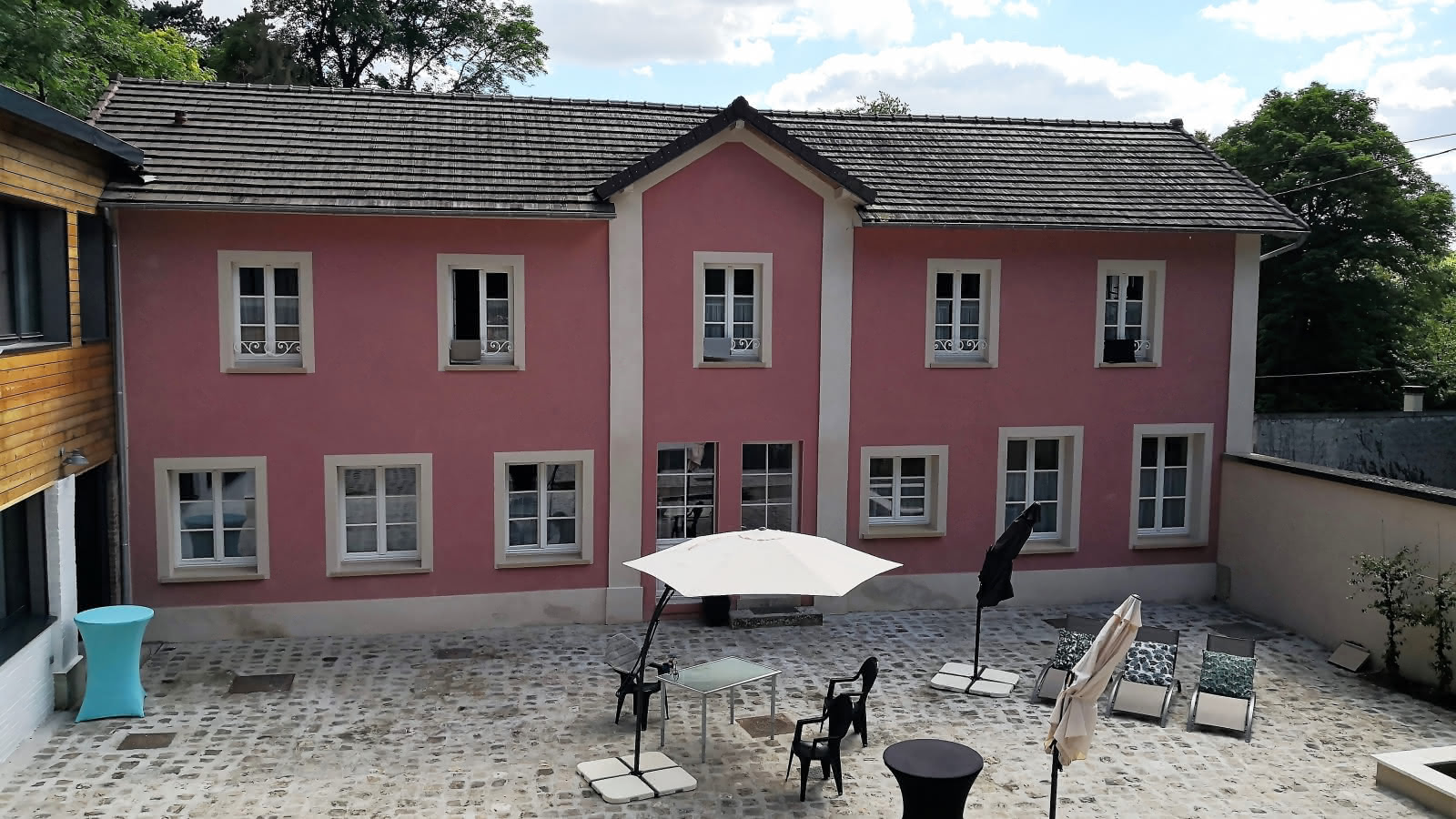 Photo de la façade extérieur rose et de sa terrasse de la chambre d'hôtes les 7 Sources à l'Isle Adam